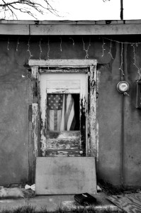 A dilapidated house surrounding an American flag.