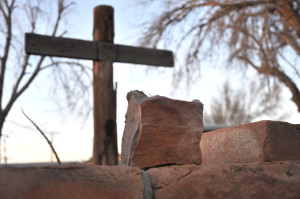 A stone in La Mesa, NM next to a make shift cross