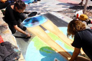 Diana Cazares drawing her painting The Same with calk on the sidewalk. The event was chalk the block.